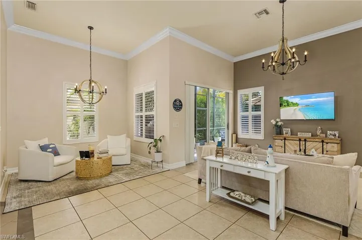 Tiled living room featuring an inviting chandelier and crown molding
