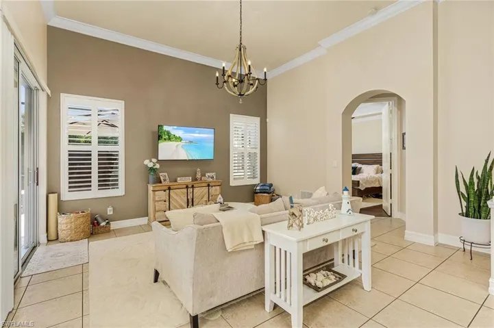 Tiled living room with a notable chandelier, a high ceiling, and crown molding