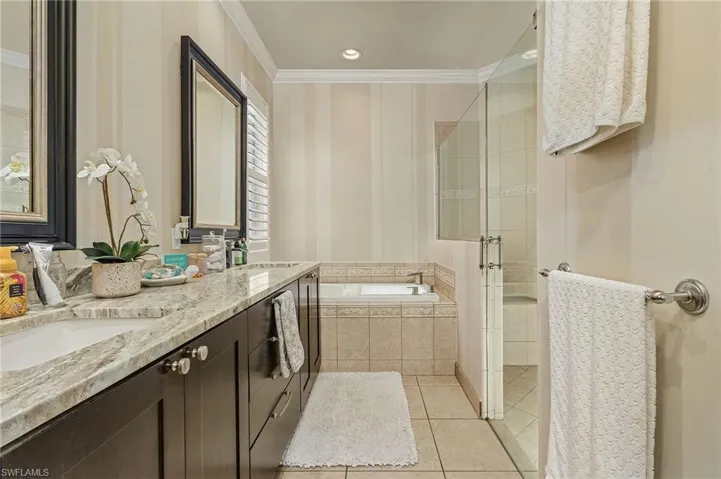 Bathroom featuring tile floors, ornamental molding, separate shower and tub, and double vanity