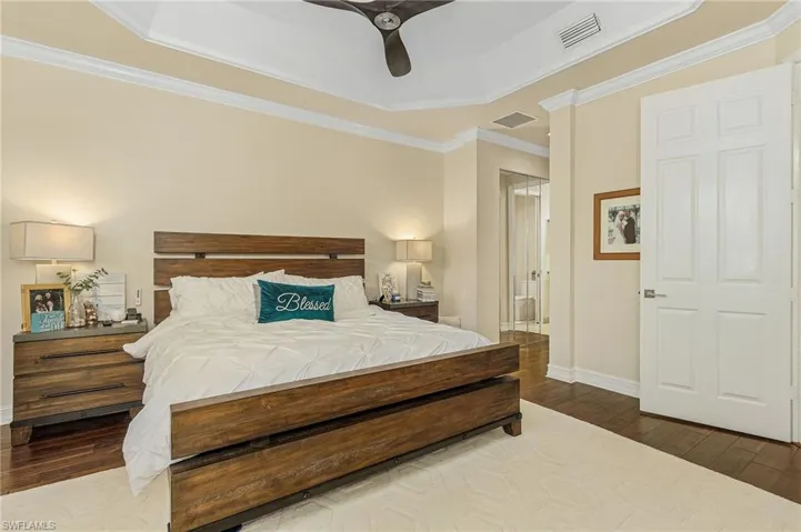 Bedroom with ceiling fan, a tray ceiling, and hardwood / wood-style floors