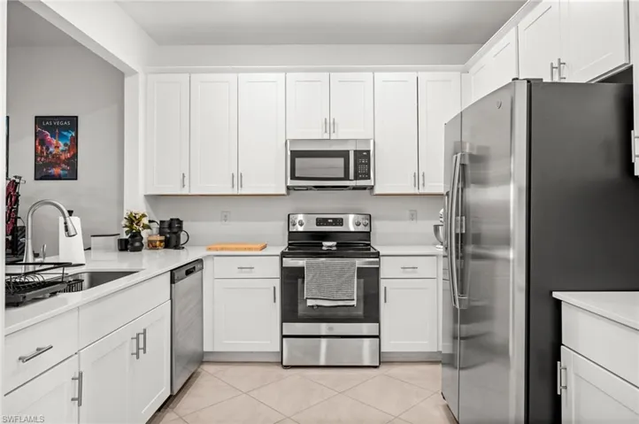 Kitchen with appliances with stainless steel finishes and white cabinetry