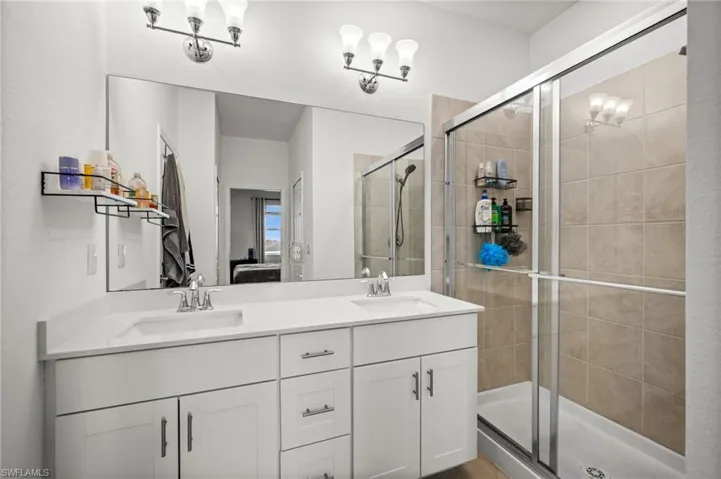 Full bathroom featuring a stall shower, connected bathroom, and double vanity