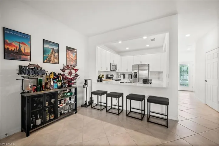 Kitchen featuring white cabinets, light tile patterned floors, a breakfast bar area, a peninsula, and appliances with stainless steel finishes