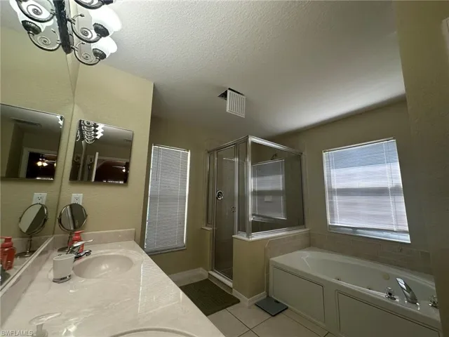 Bathroom with a shower stall, a tub with jets, visible vents, a sink, and tile patterned floors