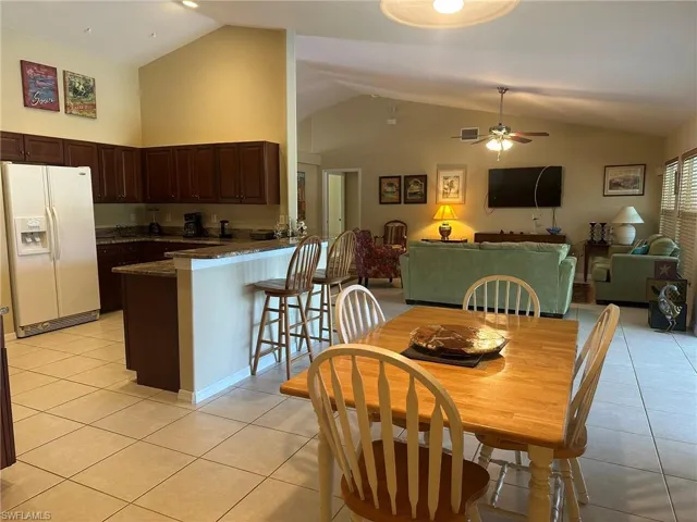 Dining area with visible vents, light tile patterned floors, a ceiling fan, and lofted ceiling