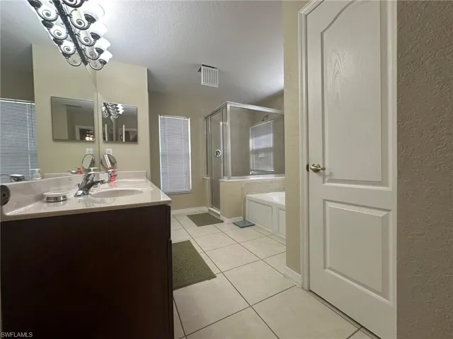 Full bathroom featuring a garden tub, a shower stall, a textured ceiling, visible vents, and tile patterned floors