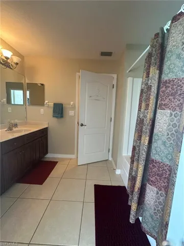 Full bathroom featuring an inviting chandelier, vanity, tile patterned flooring, visible vents, and baseboards