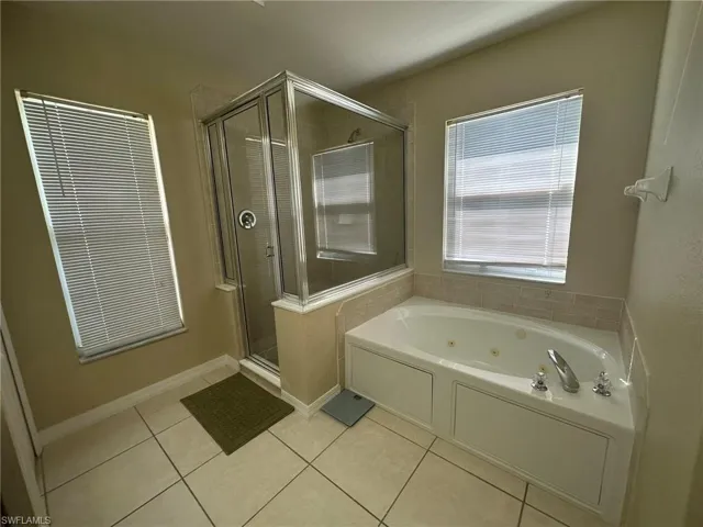 Bathroom with a whirlpool tub, tile patterned flooring, and a stall shower