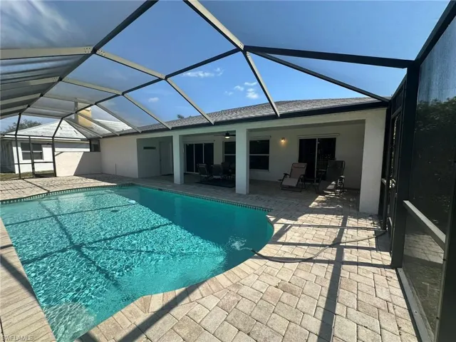 Pool with a patio, glass enclosure, and ceiling fan