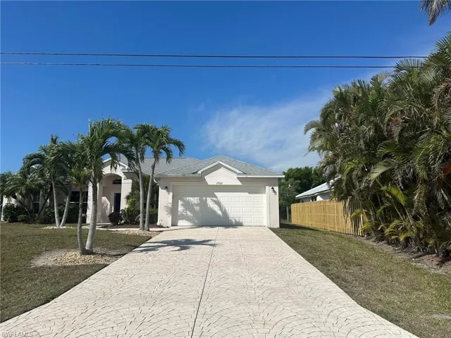 Ranch-style house with an attached garage, driveway, stucco siding, and fence