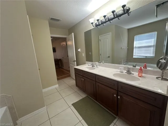 Bathroom featuring tile patterned floors, visible vents, a sink, and a garden tub
