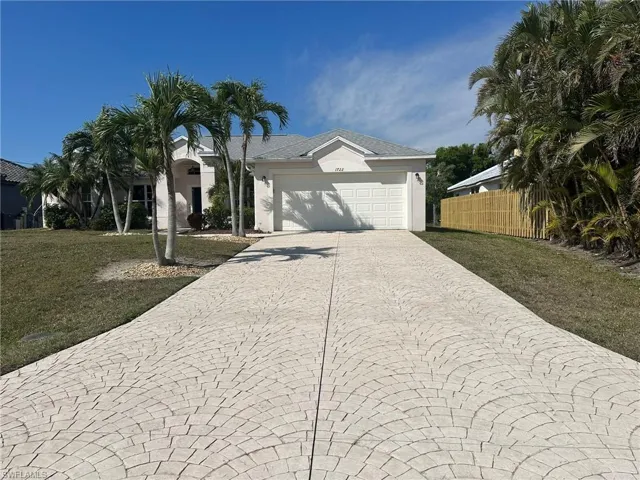 Ranch-style home featuring a garage, fence, stucco siding, a front lawn, and decorative driveway