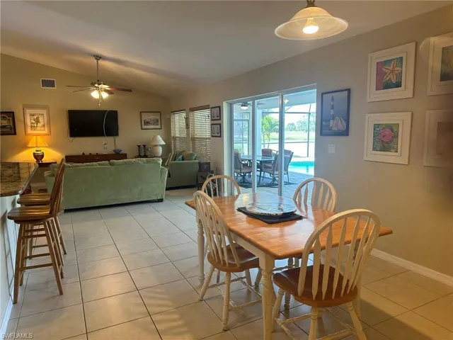 Dining room featuring visible vents, light tile patterned floors, baseboards, ceiling fan, and vaulted ceiling