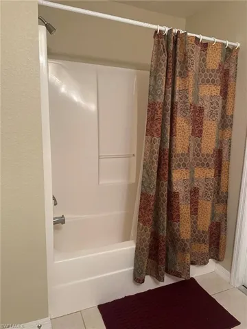 Bathroom featuring shower / bath combo, tile patterned floors, and baseboards