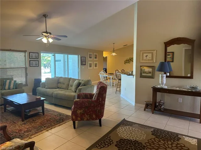 Living area featuring baseboards, a ceiling fan, light tile patterned flooring, and lofted ceiling