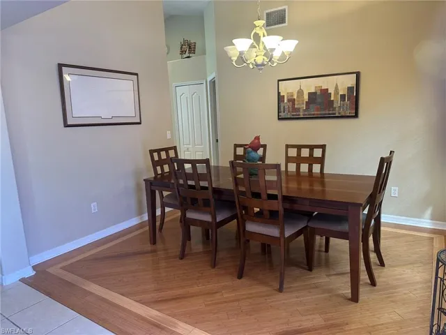 Dining room featuring a notable chandelier, baseboards, visible vents, and light wood-style flooring