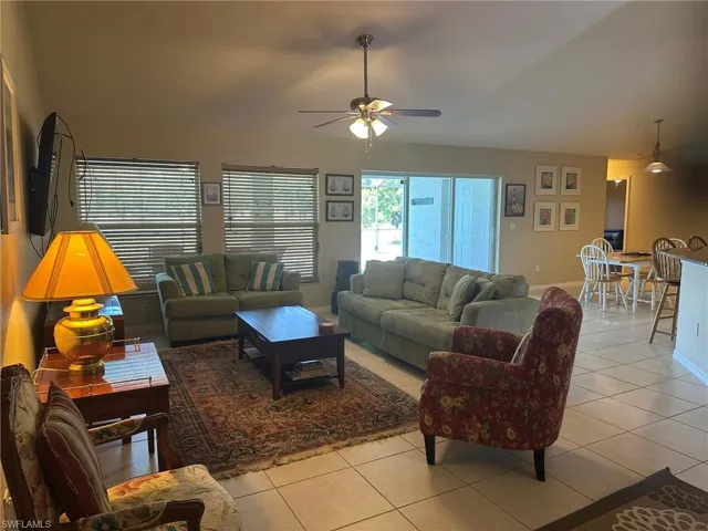 Living room with ceiling fan, baseboards, and light tile patterned flooring