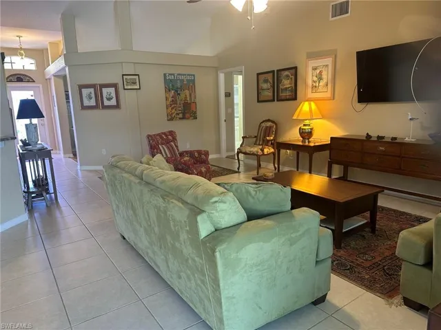 Living area with visible vents, a ceiling fan, a high ceiling, and light tile patterned floors