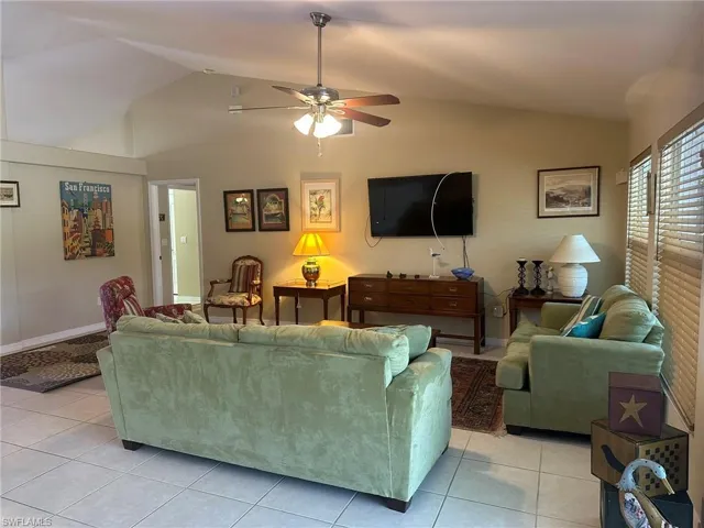 Living area with light tile patterned floors, a ceiling fan, and lofted ceiling
