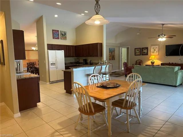 Dining space featuring high vaulted ceiling, light tile patterned floors, baseboards, and a ceiling fan