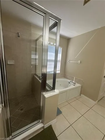 Full bath featuring a shower stall, tile patterned floors, baseboards, and a tub with jets