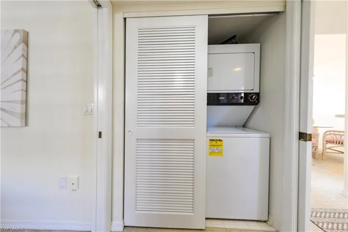 Clothes washing area featuring stacked washing matching and dryer