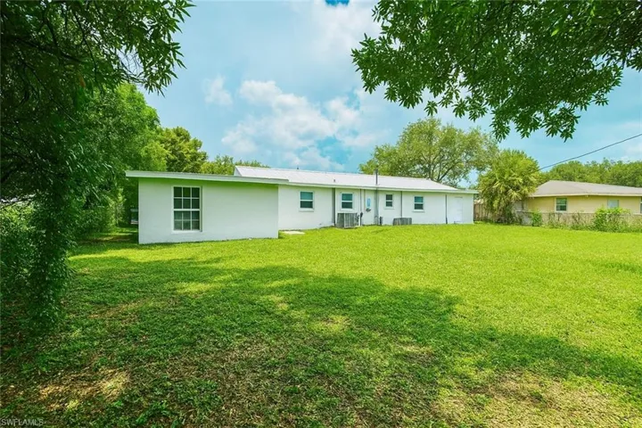 Back of property with stucco siding and a lawn