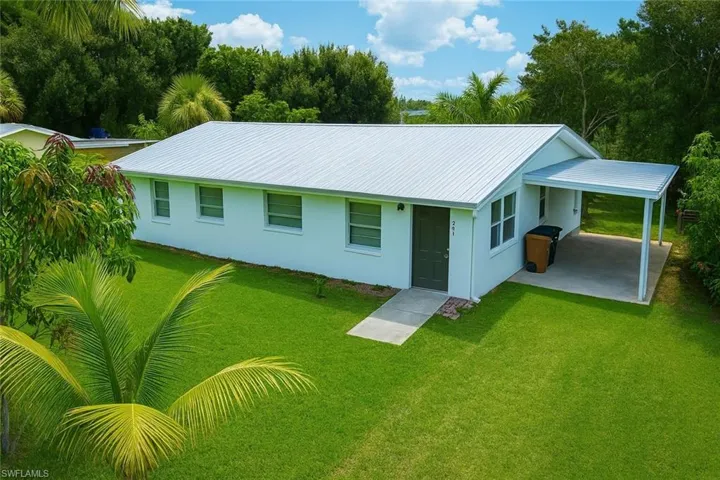 Rear view of house featuring a yard, a carport, a metal roof, and stucco siding