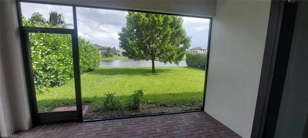 Screened patio with brick paver flooring, offering a waterfront setting, manicured lawn, and mature landscaping