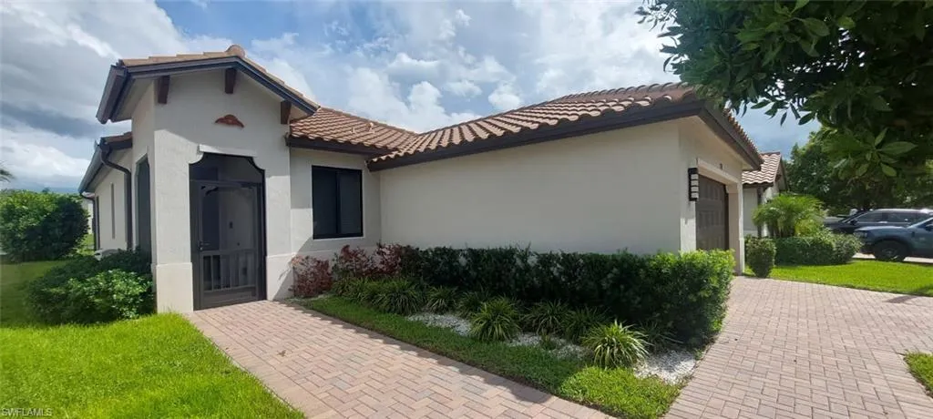 Stucco exterior with a tile roof, decorative corbels, and an enclosed front entry