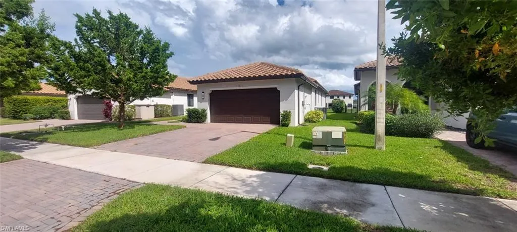 Property exterior featuring a tiled roof, paver driveway, and an attached garage