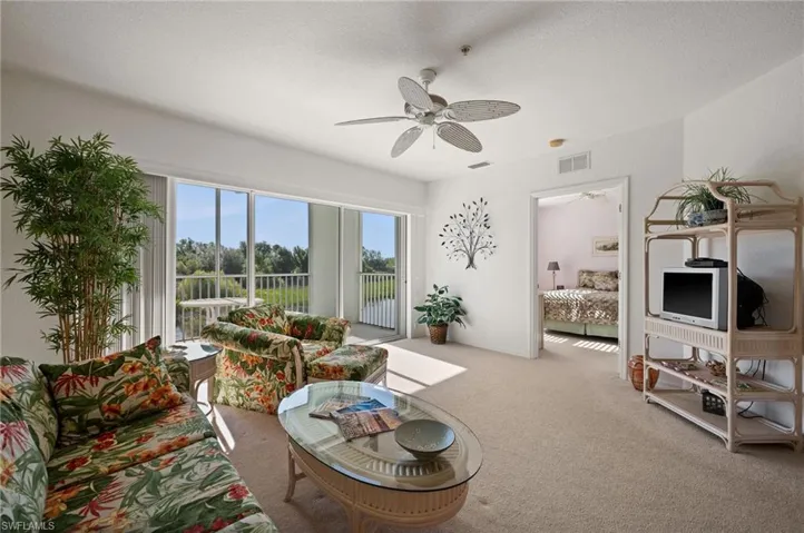 Living area featuring light colored carpet, a ceiling fan, and visible vents