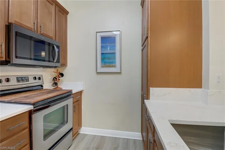 Kitchen featuring appliances with stainless steel finishes, light wood-type flooring, and light stone counters