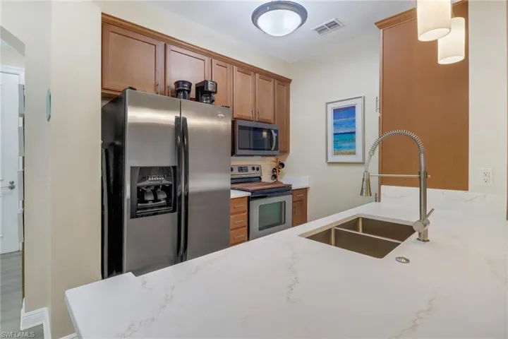 Kitchen featuring hardwood / wood-style flooring, sink, light stone counters, and stainless steel appliances