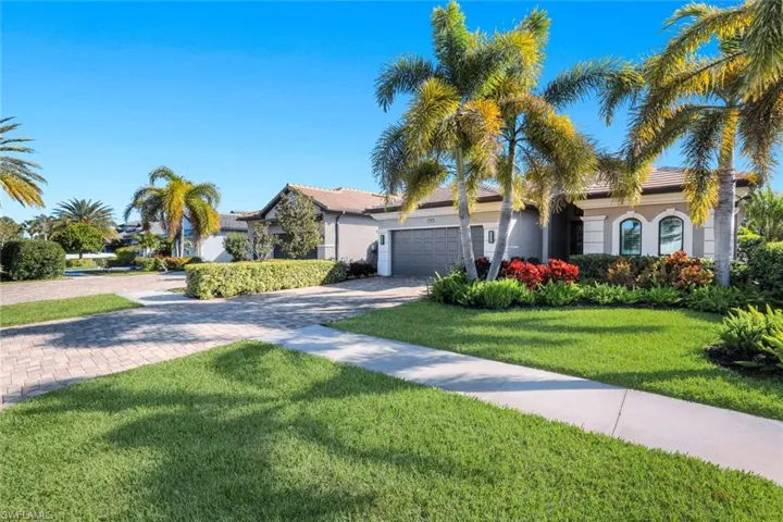 View of front facade featuring driveway, a front yard, an attached garage, and stucco siding