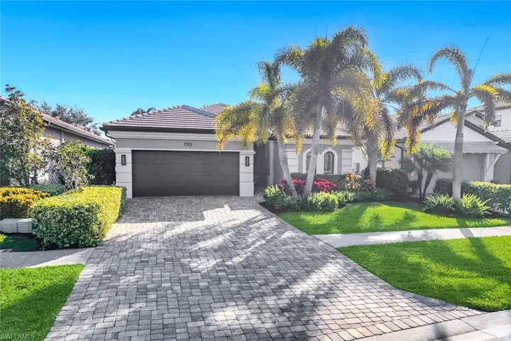 View of front facade featuring decorative driveway, a garage, a front lawn, and stucco siding