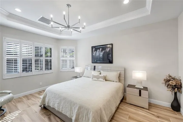 Bedroom featuring wood tiled floors, hanging lights, and crown molding