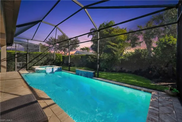 Combined pool / hot tub featuring a lanai, a patio area, a sunroom, and a fenced backyard