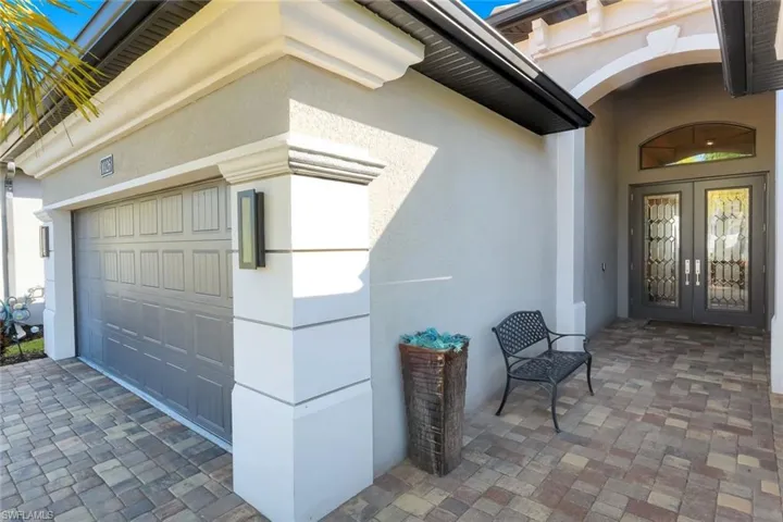 Property entrance with french doors, stucco siding, and driveway