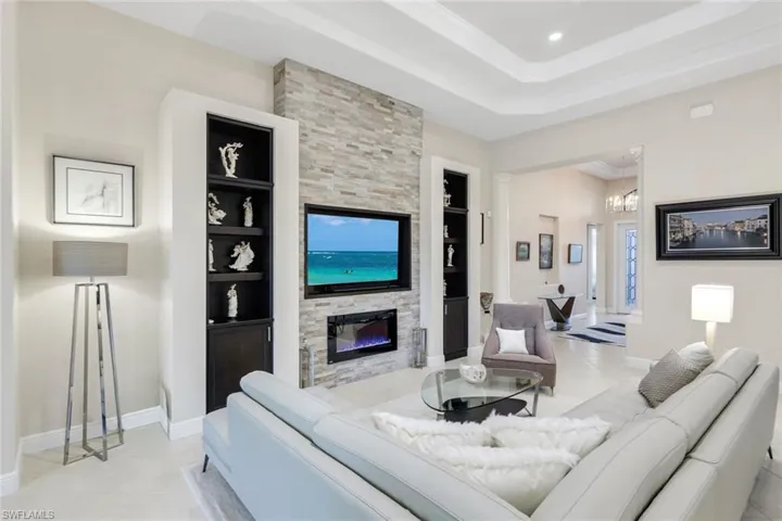 Living room featuring built in shelves, a fireplace, light tile patterned floors, a chandelier, and ornamental molding