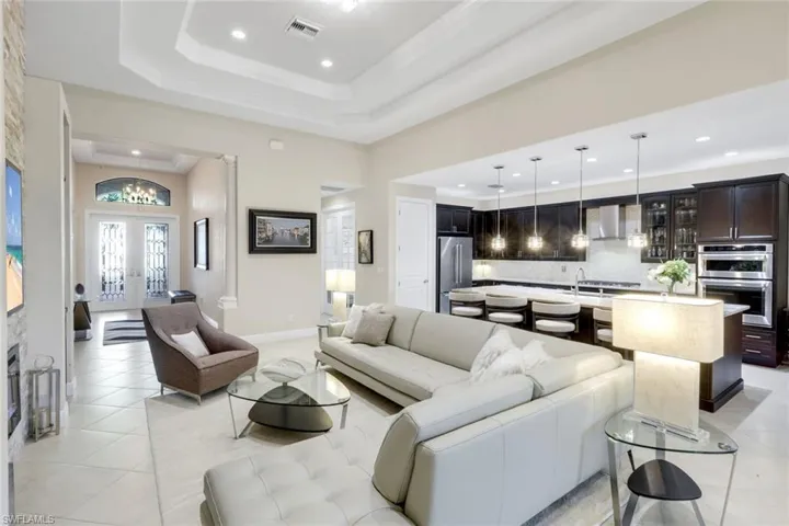 Living area with recessed lighting, french doors, light tile patterned floors, and a tray ceiling
