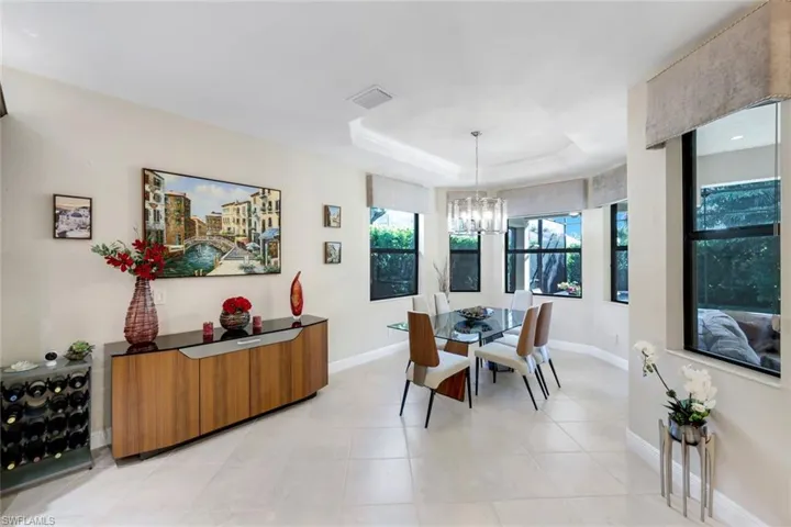 Dining space with a tray ceiling, suspended lighting, and light tile patterned floors