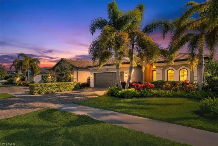 View of front of home featuring a lawn, driveway, stucco siding, and a garage