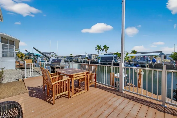 Wooden deck featuring a water view, area for grilling, outdoor dining space, and a residential view