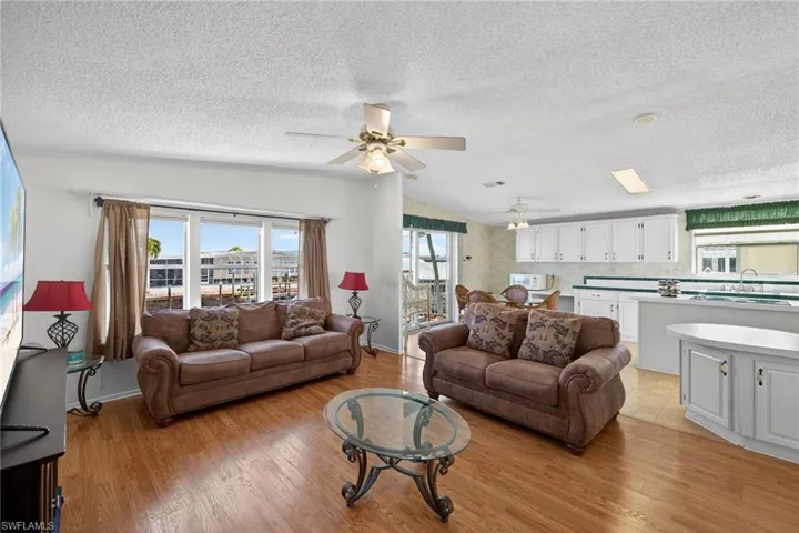 Family room featuring vaulted ceiling, a textured ceiling, ceiling fan, and light wood-type flooring