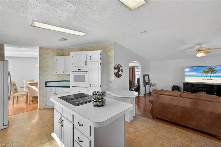 Kitchen featuring white cabinets, a center island, a textured ceiling, light countertops, and white oven