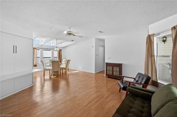 Living area with light wood finished floors, a textured ceiling, a skylight, and ceiling fan