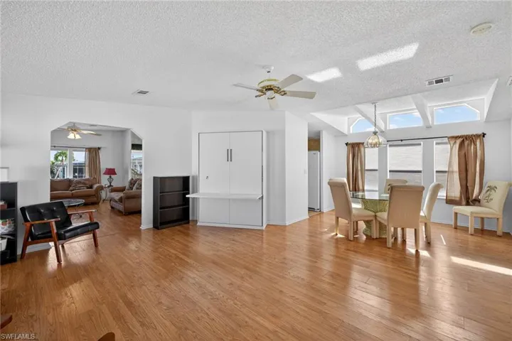 Dining area featuring a ceiling fan, light wood-style flooring, a textured ceiling, and a chandelier