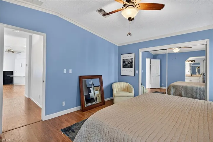 Primary Bedroom featuring crown molding, a ceiling fan, wood finished floors, a textured ceiling, and a closet