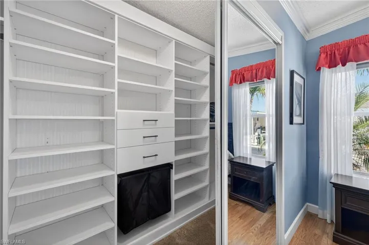 Primary closet with light wood-style flooring